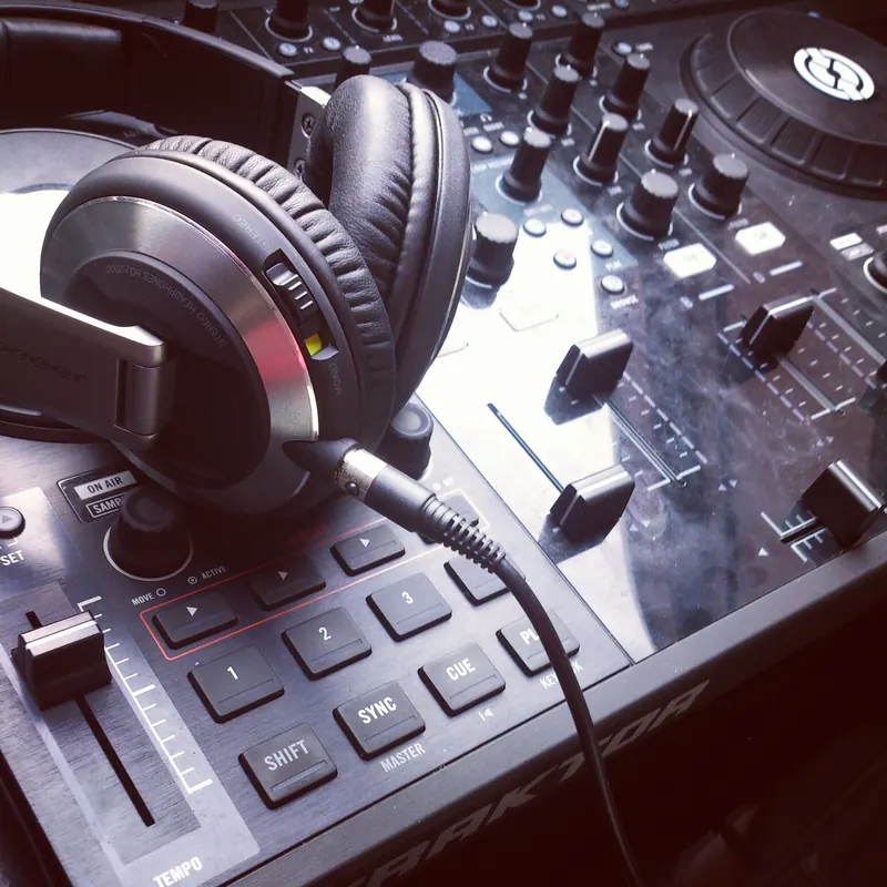 Wired Pioneer HDJ-2000 headphones with a coiled cable resting on a DJ controller