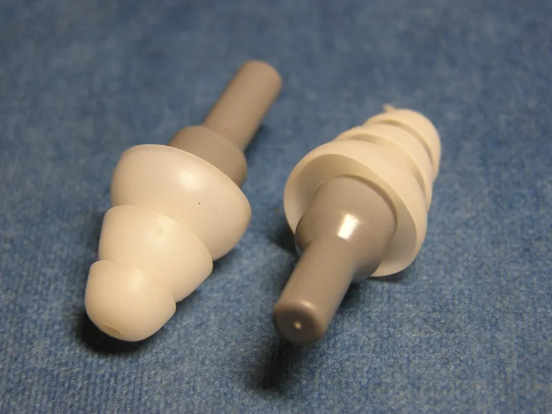 A pair of reusable flanged musician's earplugs lying on a blue cloth