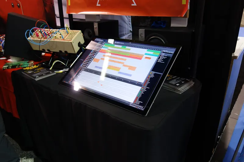 Bitwig Studio arrangement on a tilted touchscreen next to a modular synth at a trade show booth