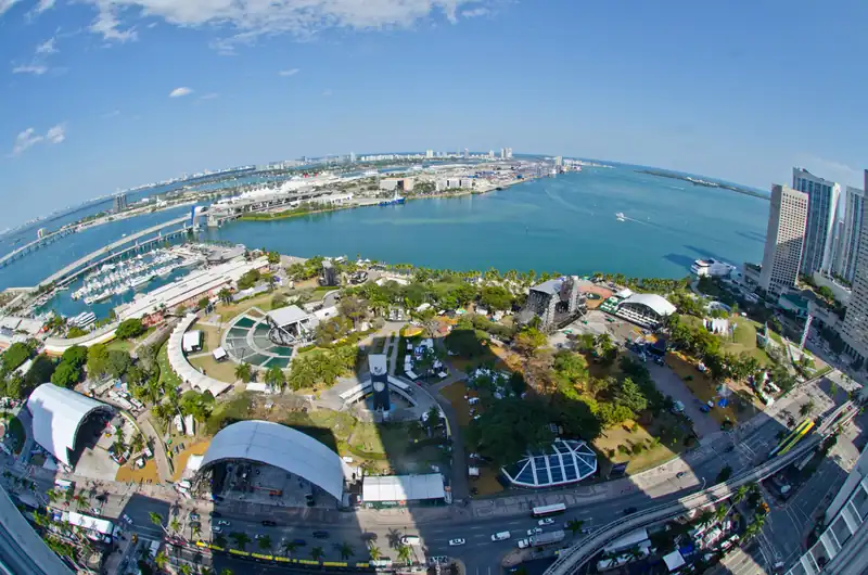 Wide view from above of Bayfront Park with Ultra's stages among the palm trees and Biscayne Bay behind